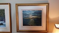 Framed oil painting of a lakeside sunset scene with a gold-tone frame, showing the entire framed artwork.