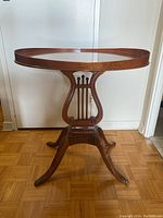 Front view of the wood pedestal table showing the round top with raised rim and clawfoot legs.