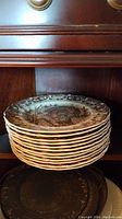 Stack of twelve His Majesty turkey dinner plates on wooden shelf