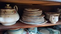 Shelf view with teapot, stacked dinner and side plates, sugar bowl