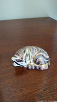 Side view of sleeping cat figurine displaying painted brushstroke stripes and gold gilt accents