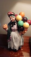Front view of the Royal Doulton figurine showing the woman with colorful balloons and period attire.