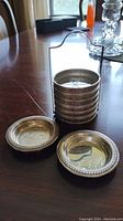 Six coaster rims stacked in stand with two dishes in front on table