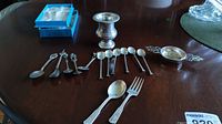 Overview of all lot contents, including souvenir spoons, demitasse spoons, serving spoon and fork, tea strainer and bud vase