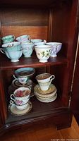 Shelf display with eleven assorted teacup and saucer sets