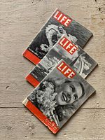 Four vintage Life magazines from the 1940s spread on a wooden surface, showing their front covers