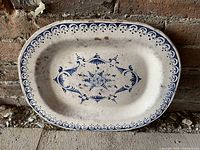 Top view of the antique rectangular platter showing central blue floral design and blue border pattern on white base, with wear marks and chips.