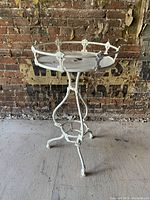Full view of antique Victorian white painted wrought iron planter table with decorative leaf and fleur finials on round tray and legs.