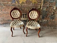 Pair of vintage side chairs with carved wooden frames and velvet tufted seats and backs, showing overall front view.