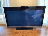 Front view of 55 inch Sony Bravia TV with the screen displaying HDMI 3 input and no signal message, mounted on a rectangular black stand placed on wooden floor.