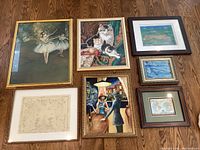 Seven assorted framed vintage art prints and originals on hardwood floor showing arrangement and range of sizes.