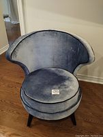Front view of blue velvet accent chair showing curved backrest and round cushion with dark piping.