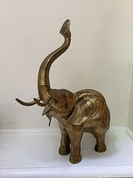 Side angle of brass elephant statue showing raised trunk and tusks