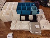 Overview of the entire large collection of IKEA collapsible fabric storage cases in various sizes and colors arranged on wooden floor.
