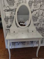 Front view of white IKEA vanity with oval mirror and glass top.