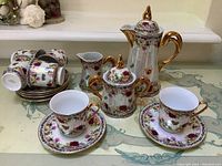 Full view of entire tea set displayed on table, arranged to show all main pieces including cups, saucers, teapot, sugar bowl, creamer