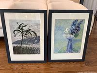 Front view of the pair of signed original paintings in blue frames showing tree and floral subjects