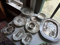 Overview of all pieces on table under window, showing platter, bowls, plates, leaf dishes