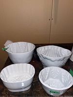 Four white ironstone pudding molds of different shapes and patterns on a dark surface