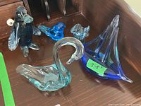 Five glass figures arranged on wooden surface showing full lot