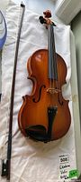 Violin and bow laid on white cloth, full view