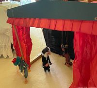 Puppet theater set up with three marionette puppets suspended inside the stage, showing the scale and setup.