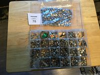 Top down photo of plastic organizer box with multiple compartments holding various letter and character metal pieces plus sealed plastic bags with more pieces.