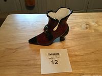 Ceramic Victorian-style ladies' shoe figurine placed on wooden surface with lot number card visible.