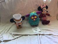 Overview of all three items: Mickey Mouse cup, Furby toy, Minnie Mouse plush