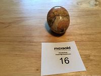 Jasper crystal sphere placed on wooden surface showing earth-tone pattern and smooth polished finish.