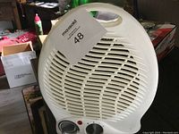 Front view of the white Matsoldo electric fan heater showing circular grill, carry handle, and control knobs.