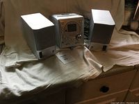 Magnasonic stereo system with two satellite speakers on either side, placed on a cloth-covered surface.