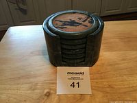 Stack of round green marble coasters in matching marble holder on wooden surface