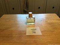 Photo showing new bottle of Celine Dion perfume on a wooden surface with lot number in front.