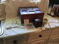 Photo of the wooden photo frame jewelry box with six photo slots, smaller music box, wind chimes, and assorted jewelry items on a cloth-covered surface.