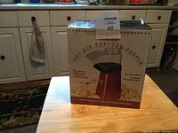 Photo of boxed Maxsold hot air popcorn popper on wooden table in kitchen setting