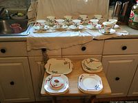 Nine cups and saucers arranged on counter under cloth