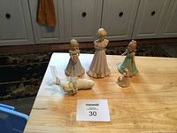 Photo of five porcelain figurines on wooden table showing front view of three Growing Up Birthday Girls, one Debra 1995, and one Snow Baby figurine