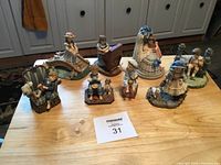 Overall view of the 8 little statues featuring children in various poses and outfits arranged on a wood surface.