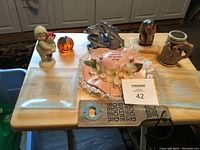Photo capturing the assorted items on a wooden table including plates, figurines, and a bottle opener.