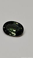 Close-up image of the natural oval cut forest green sapphire gemstone, showing clarity and cut details.
