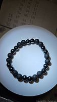 Photo of natural black lavastone and hematite gemstone chunky bead bracelet, beads approximately 8mm, stretched in a circle with mix of porous lavastone and smooth hematite beads.