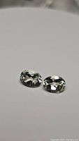 Two oval cut green amethyst/prasiolite gemstones on a neutral background showing clarity and color.