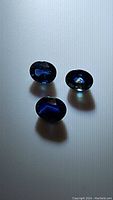 Three natural blue oval cut sapphires reflecting light and showing deep blue color.