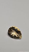 Close-up photo of a pear cut natural citrine gemstone with golden color.