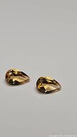 Pair of natural golden citrine gemstones shown on a neutral background, well-lit to display color and clarity.