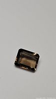 Natural smokey quartz gemstone with emerald cut, showing its color and clarity on white background.