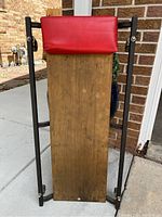 Top side view of red padded headrest and wooden board base of creeper