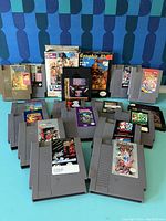 Front view of loose NES cartridges and two Koei boxed games against blue patterned backdrop