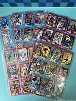Front view of multiple colorful Marvel character trading cards in plastic sleeves arranged on a blue surface.